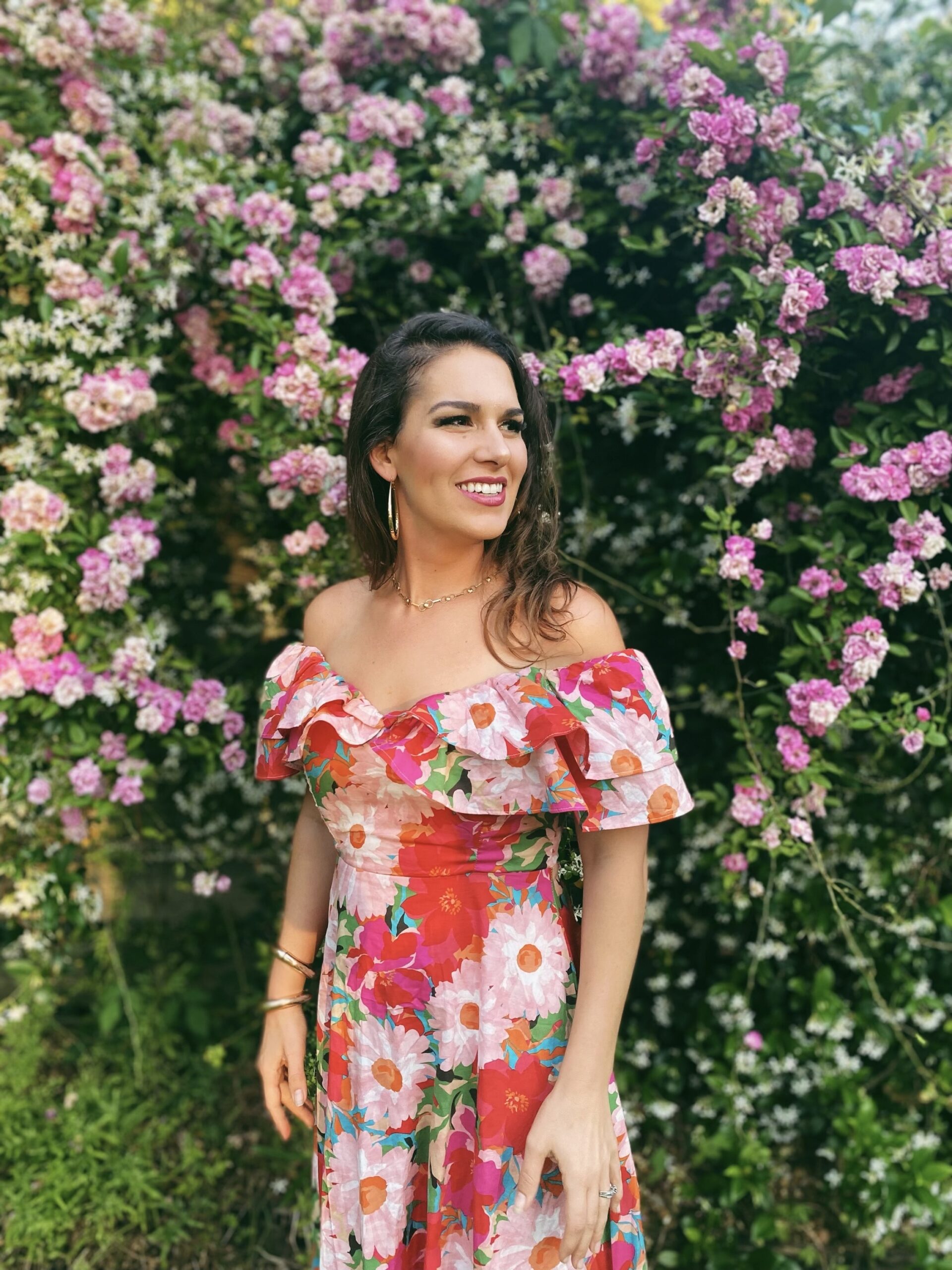 Rachael Riley smiling in front of a wall of flowers